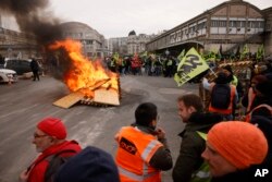 Aksi mogok kerja para pekerja kereta api di dekat palet yang terbakar di stasiun kereta Gare de Lyon, Paris, Prancis, Selasa, 28 Maret 2023. (AP/Thomas Padilla)