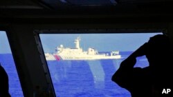 FILE - In this photo provided by the Philippine Coast Guard, a Chinese Coast Guard ship sails near a Philippine Coast Guard vessel during its patrol at Scarborough Shoal, March 2, 2022. 