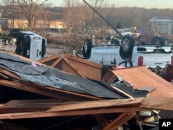 FILE - Upturned vehicles are seen next to damaged structures after a tornado swept through Coralville, Iowa, March 31, 2023.