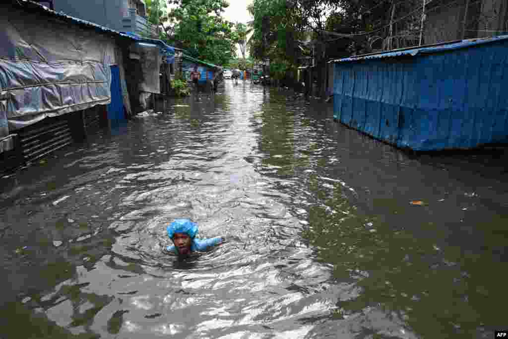 Момче плива низ надојдените води по силниот дожд во Јангон, Мјанмар.