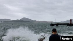 A man watches the waves at the seaside as Typhoon Talim approaches, in Hong Kong, China, July 17, 2023.
