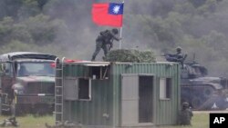 Seorang tentara memegang bendera nasional Taiwan selama latihan simulasi pertempuran darat dan udara terpadu di Kabupaten Hsinchu, Taiwan utara, Kamis, 21 September 2023. (AP/Chiang Ying-ying)