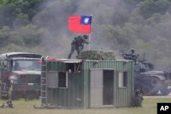 Seorang tentara memegang bendera nasional Taiwan selama latihan yang mensimulasikan pertempuran darat dan udara terpadu di Kabupaten Hsinchu, Taiwan utara, Kamis, 21 September 2023. (Foto: AP/Chiang Ying-ying)