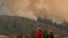 Dua orang anak menyaksikan upaya pemadaman kebakaran di tengah asap tebal dari kebakaran hutan Eagle Bluff di Osoyoos, British Columbia, Kanada. Kebakaran ini melintasi perbatasan Kanada-AS dari negara bagian Washington dan memicu perintah evakuasi.(Reuters)&nbsp;