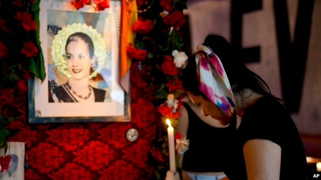 FILE - A waitress lights a candle on an altar dedicated to Argentine former first lady Eva Perón, or Evita, at the Santa Evita restaurant in the Palermo neighborhood of Buenos Aires, Argentina, Jan. 28, 2024.