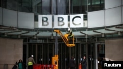 FILE - Repairmen work next to a sign at the British Broadcasting Corporation (BBC) headquarters in London, March 13, 2023. 