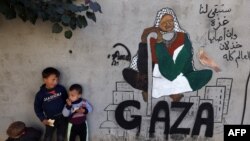 Displaced Palestinian children stand next to a mural painting by artist Amal Abo in Rafah in the southern of Gaza Strip, Dec. 31, 2023.