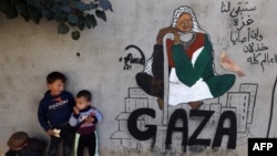 Anak-anak pengungsi Palestina berdiri di samping lukisan mural karya seniman Amal Abo di Rafah di selatan Jalur Gaza, pada 31 Desember 2023. (Hewan-hewan di kebun binatang di Rafah, kota di Gaza Selatan, sekarat karena kelaparan. (Foto: Ilustrasi/AFP)