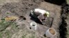 Nebraska State Archeologist Dave Williams clears away soil as workers dig for the forgotten cemetery with the suspected remains of children who once attended the Genoa Indian Industrial School, July 10, 2023, in Genoa, Neb.