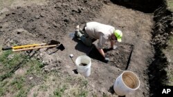 Nebraska State Archeologist Dave Williams clears away soil as workers dig for the forgotten cemetery with the suspected remains of children who once attended the Genoa Indian Industrial School, July 10, 2023, in Genoa, Neb.
