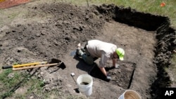 Nebraska State Archeologist Dave Williams clears away soil as workers dig for the forgotten cemetery with the suspected remains of children who once attended the Genoa Indian Industrial School, July 10, 2023, in Genoa, Neb.