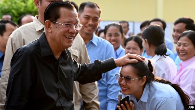 Member of parliament and Cambodia's former prime minister Hun Sen (L) greets commune councilors after he cast his vote at a polling station during the Senate election in Takhmao city, Kandal province on Feb. 25, 2024.