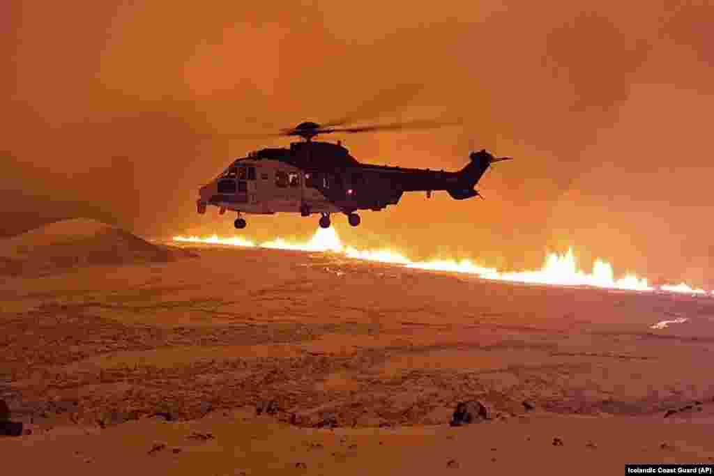 This image made from video provided by the Icelandic Coast Guard shows its helicopter flying near magma running on a hill near Grindavik on Iceland&#39;s Reykjanes Peninsula.