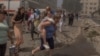 A woman carries a girl next to a heavily damaged building of the Ohmatdyt children's hospital following a Russian missile strike in the Ukrainian capital of Kyiv, July 8, 2024.