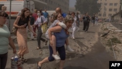 A woman carries a girl next to a heavily damaged building of the Ohmatdyt children's hospital following a Russian missile strike in the Ukrainian capital of Kyiv, July 8, 2024.