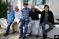FILE - The Waldos, from left, Mark Gravitch, Larry Schwartz, Dave Reddix, Jeffrey Noel and Steve Capper sit on a wall they used to frequent at San Rafael High School in San Rafael, California, April 13, 2018.