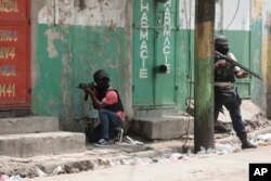 FILE - Police officers take cover during an anti-gang operation in the Portail neighborhood of Port-au-Prince, Haiti, April 25, 2023.