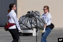 FILE - Recovery team members carry a capsule containing NASA's first asteroid samples to a temporary clean room at Dugway Proving Ground in Utah on Sunday, Sept. 24, 2023. (AP Photo/Rick Bowmer, Pool)