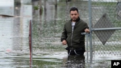 Francisco López se encuentra cerca del estacionamiento inundado de su edificio de apartamentos, el jueves 13 de junio de 2024, en Hallandale, Florida.