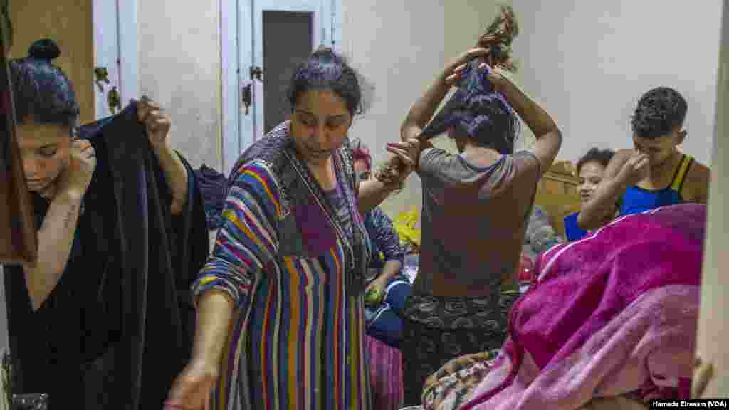 Waffa, a single mother who lives with over a dozen family members, including nine children, combs her daughter Mariam&rsquo;s hair as her nephews dress up in their new Eid outfits from a local charity.