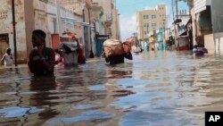 In this image made from video, men walk through floodwaters in the town of Beledweyne, Somalia, Nov. 19, 2023. 