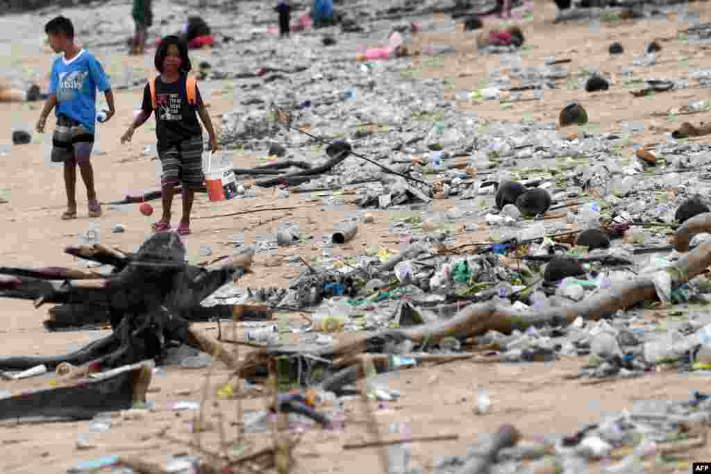 Children walk past plastic and other trash washed ashore at Kedonganan Beach, Badung regency, on Indonesia&#39;s resort island of Bali.