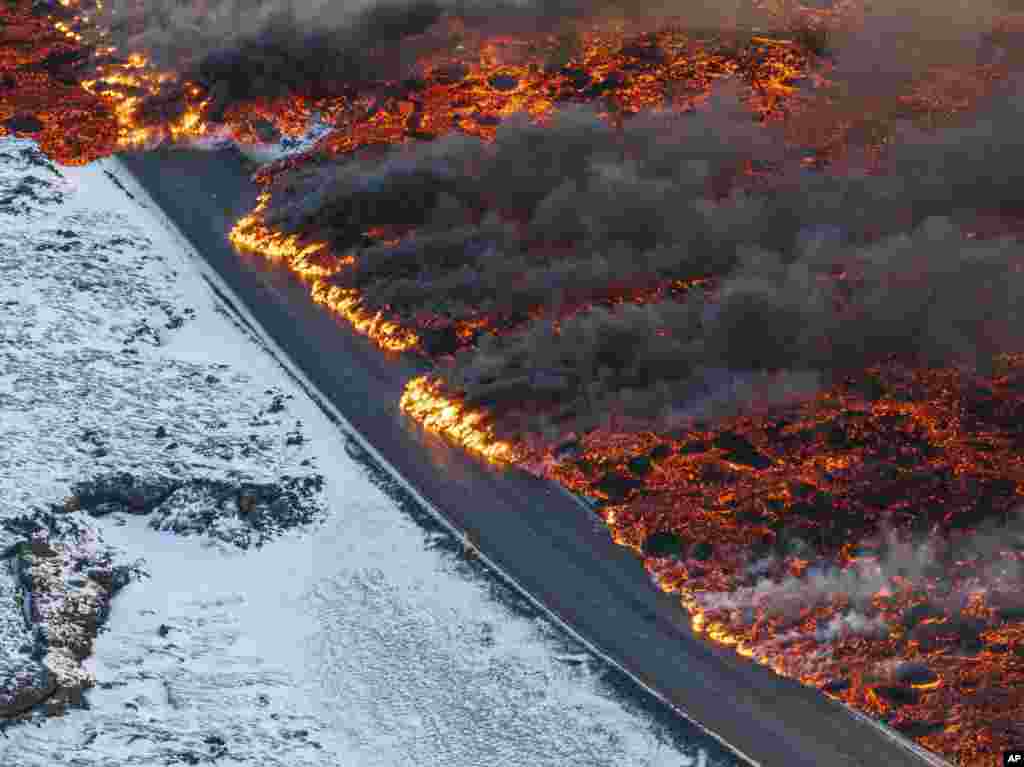 A view of lava crossing the main road to Grindavík and flowing on the road leading to the Blue Lagoon, in Grindavík, Iceland.&nbsp;A volcano in southwestern Iceland has erupted for the third time since December and sent jets of lava into the sky.