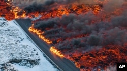 A view of lava crossing the main road to Grindavík and flowing on the road leading to the Blue Lagoon, in Grindavík, Iceland.&nbsp;A volcano in southwestern Iceland has erupted for the third time since December and sent jets of lava into the sky.