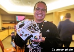 Mdewakanton Dakota artist Cole Redhorse Taylor, a member of the Prairie Island Indian Community in Minnesota, poses with a controversial helmet he designed for Minnesota Wild hockey goalie Marc-Andre Fleury.