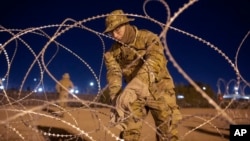 BESTAND – Een soldaat van de Nationale Garde van Texas bindt rijen prikkeldraad vast die in de vroege uren van 11 mei 2023 moeten worden geïnstalleerd bij een grenshek in El Paso, Texas.
