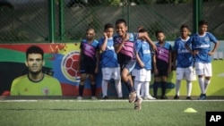 Young soccer players train at the Club Bayer soccer school that was founded by Luis Manuel Diaz, father of the Colombian player and Liverpool striker Luis Diaz, featured on the wall at left, in Barrancas, Colombia, Nov. 8, 2023.