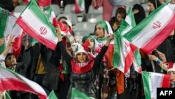 FILE - Female football fans wave Iranian national flags during the friendly football match between Iran and Russia at Azadi Stadium in Tehran, on March 23, 2023. The head of the Iranian Football Federation has renewed a vow to allow women into various stadiums in the country. 