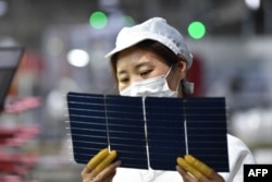 A worker checks solar photovoltaic modules used for solar panels at a factory in Suqian in China's eastern Jiangsu province, May 9, 2023.