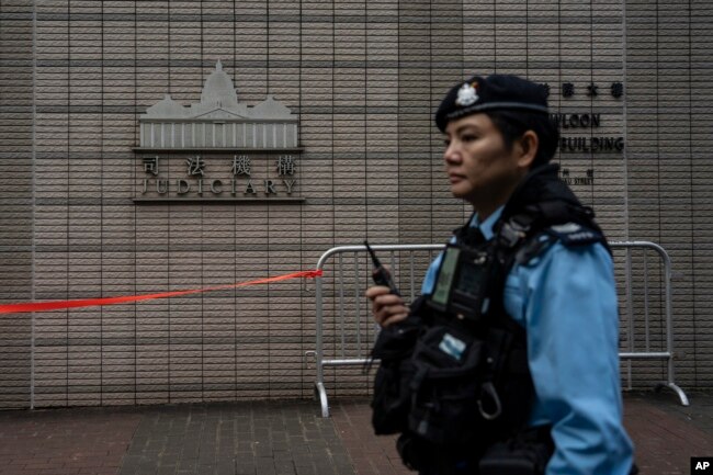 A police officer walks past the entrance of West Kowloon Magistrates' Courts, where activist publisher Jimmy Lai's trial is scheduled to open, in Hong Kong, Monday, Dec. 18, 2023. (AP Photo/Vernon Yuen)