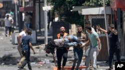 FILE - Palestinians carry a wounded man shot by Israeli fire in the Jenin refugee camp, in the occupied West Bank, July 4, 2023.