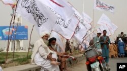 FILE - Elderly men sit under Taliban flags as Afghanistan's de facto rulers mark the second anniversary of the withdrawal of U.S.-led troops from the country, in Kandahar, south of Kabul, Aug. 15, 2023.