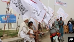 FILE - Elderly men sit under Taliban flags as Afghanistan's de facto rulers mark the second anniversary of the withdrawal of U.S.-led troops from the country, in Kandahar, south of Kabul, Aug. 15, 2023.
