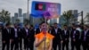 在中国杭州举行的第19届亚运会欢迎仪式上，一名志愿者举牌站在阿富汗塔利班政权派出的全部为男性运动员的队伍前。（2023年9月20日）