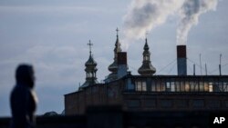 FILE - A woman walks with a power plant in the background, in Vinnytsia, Ukraine, March 16, 2022. Russia launched a cyberattack against a power plant near Kyiv in March 2023 and followed up with a missile strike shortly after the Ukrainian cyber response team arrived. 