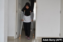 Siti Khotimah berjalan menggunakan alat bantu setelah mengalami kekerasan fisik dari majikannya saat dia bekerja sebagai pembantu rumah tangga, Jakarta, 27 Juli 2023. (Foto: Adek Berry/AFP)