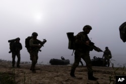 Ukrainian servicemen walk on the shore of Dnipro River after exiting a boat at the front line near Kherson, Ukraine, Oct. 15, 2023.