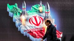 Seorang pria berjalan melintasi spanduk yang menampilkan gambar peluncuran rudal yang dihiasi dengan bendera Iran di pusat Teheran pada 15 April 2024. (Foto: AFP)