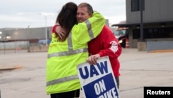 FILE - Striking United Auto Workers union members embrace at the end of their picket shift outside the Ford Michigan Assembly Plant in Wayne, Michigan, Oct. 25, 2023.