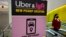 FILE - A passer-by walks past a sign offering directions to an Uber and Lyft ride pickup location at Logan International Airport, in Boston, Feb. 9, 2021. 