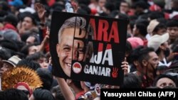 Seorang pendukung mengangkat poster calon presiden dan mantan gubernur Jawa Tengah Ganjar Pranowo saat kampanye pemilu di Stadion Gelora Bung Karno, Jakarta pada 3 Februari 2024. (Foto: Yasuyoshi Chiba/AFP)