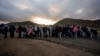 Asylum-seeking migrants line up in a makeshift, mountainous campsite to be processed after crossing the border with Mexico, Feb. 2, 2024, near Jacumba Hot Springs, California.