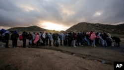 Asylum-seeking migrants line up in a makeshift, mountainous campsite to be processed after crossing the border with Mexico, Feb. 2, 2024, near Jacumba Hot Springs, California.