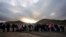 FILE - Asylum-seeking migrants line up in a makeshift, mountainous campsite to be processed after crossing the border with Mexico, Feb. 2, 2024, near Jacumba Hot Springs, California.