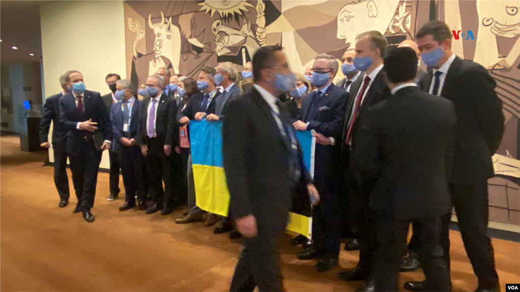 Embajadores en Naciones Unidas posaron con una bandera de Ucrania fuera de la sala del Consejo de Seguridad donde se llevó acabo una reunión de emergencia para abordar la acción militar de Rusia tras el inicio de la invasión a Ucrania, el 25 de febrero de 2022, en la sede de la ONU en Nueva York.