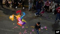 Seorang anak memukul piñata di Mexico City, Jumat, 22 Desember 2023. (AP Photo/Marco Ugarte)